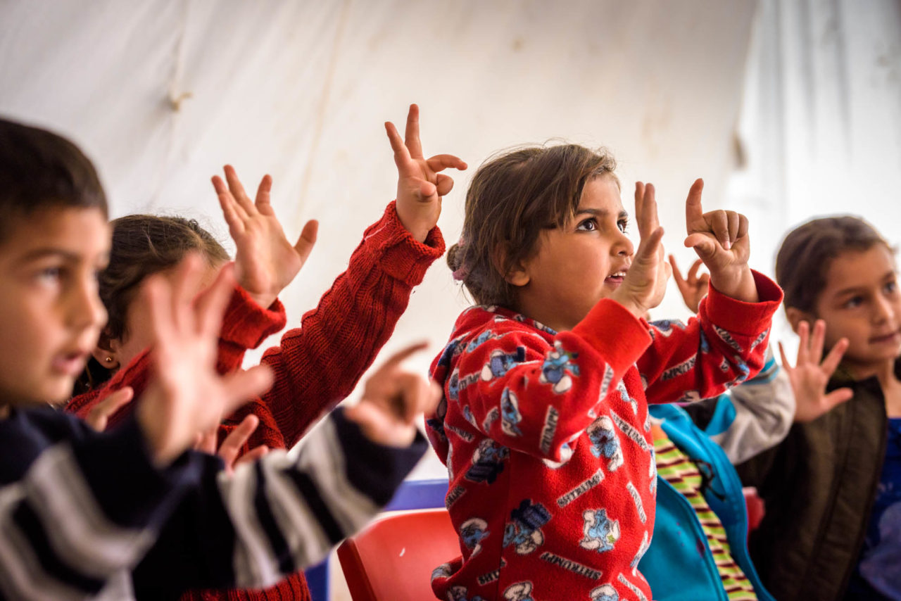 Samira Al Allawi, 5 (wearing red shirt that looks like pajamas)  participates in activities at the early childhood education center in Rajab, an informal tented settlement in the Bekaa Valley, Lebanon. Syrian refugee children ages 3 to 6 attend World Vision’s Early Childhood Education program at Rajab, an Informal Tented Settlement for Syrian refugees in the Bekaa Valley, Lebanon. The center opened in February 2016. Students learn English, math, Arabic, and science taught with a lot of songs and activities. In a half-day session, there’s also time for play and a meal.   Activities at the Early Childhood Education center offer the first experience of directed group activities for many of the children.